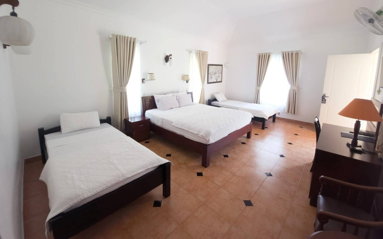 Ein Hotelzimmer mit zwei Betten, einem Schreibtisch, einem Sessel, einer Lampe und einem Bild an der Wand.