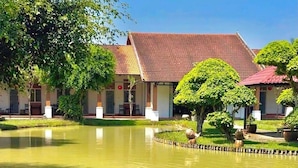A traditional building with a tiled roof, surrounded by a pond with swans. - Les Hameaux de l'Orient (Ho Chi Minh City)