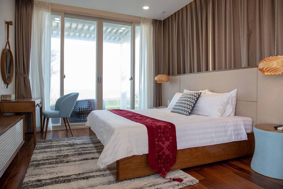 Un dormitorio con cama, escritorio, silla y vistas al exterior.