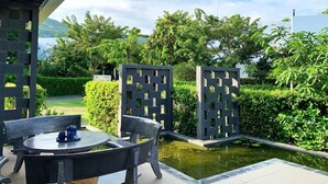 A patio with a table and chairs, a small water feature, and a view of a lush garden and distant mountains. - Viva Villa Oceanami (Nam Nha Trang)