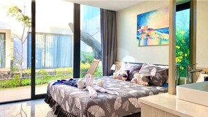 A modern hotel room with a large bed, a view of greenery, and a painting on the wall. - Viva Villa Oceanami (Nam Nha Trang)