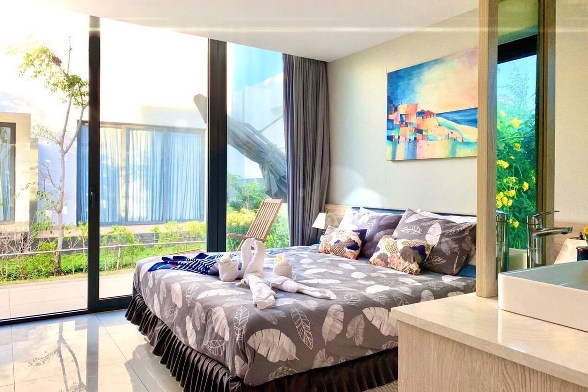 Habitación de hotel moderna con una cama grande, vistas a zonas verdes y un cuadro en la pared.