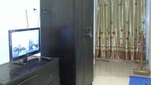 Una habitación con televisor sobre una cómoda, un armario y una cortina.