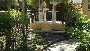 Un jardín tropical con un sendero que conduce a un pequeño santuario.