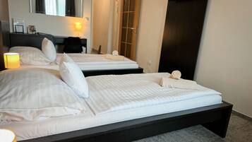 A hotel room with two beds, a desk, a chair, a lamp, and a TV.
