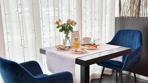 A dining table with a menu, plates of food, and a cup of coffee. There are two blue chairs around the table. - Hotel Modena (Bratislava)