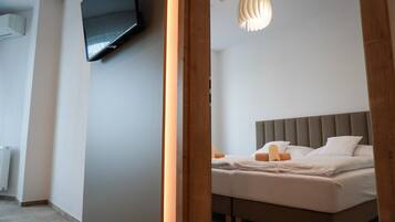 A modern bedroom with a large bed, a mounted TV, and a unique ceiling light fixture.