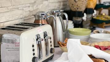 A kitchen with a white toaster, a kettle, and various kitchen utensils.