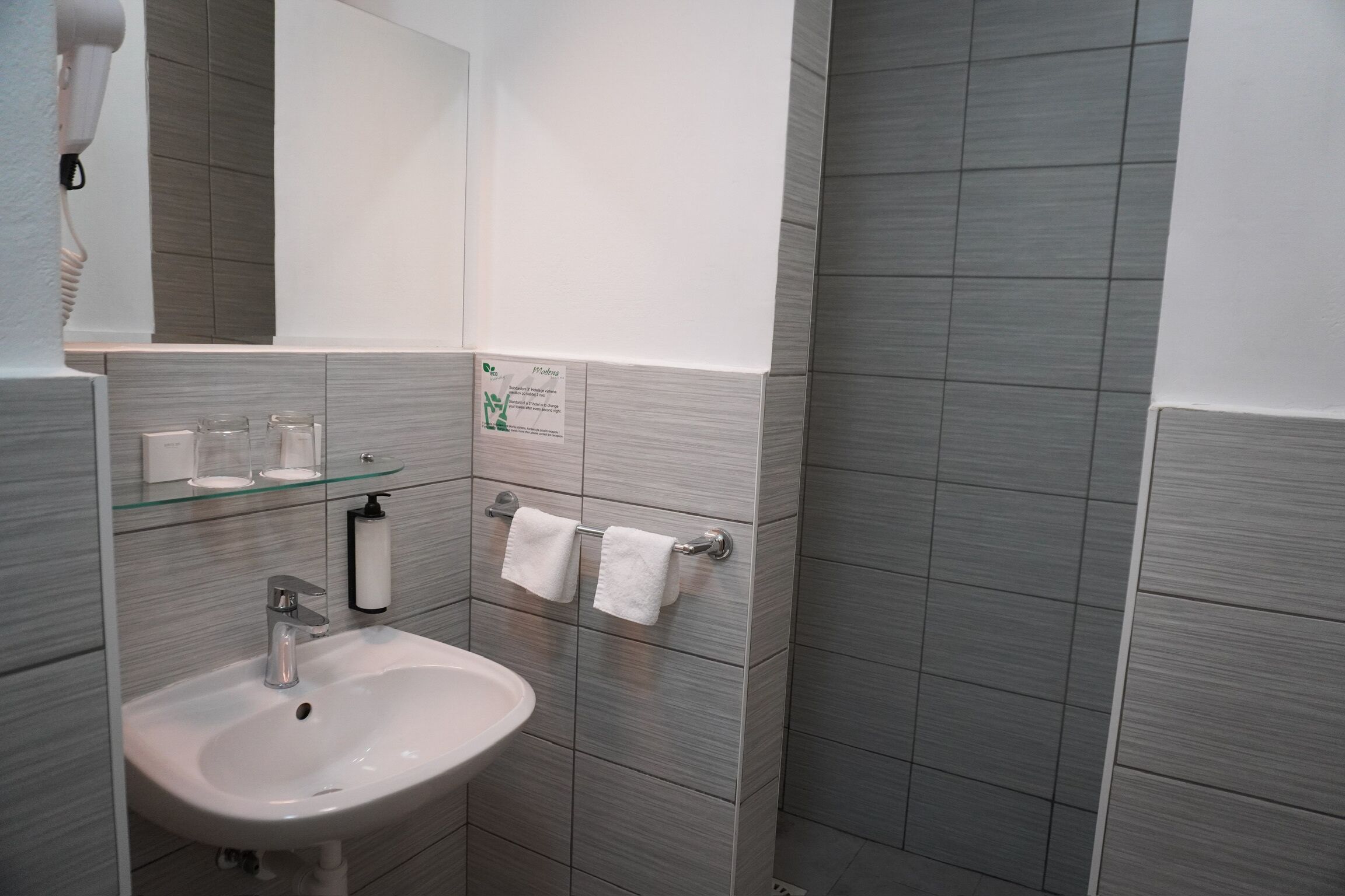 Un baño con lavamanos, espejo, toallero y secador de pelo.