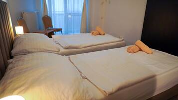 Ein Hotelzimmer mit zwei Betten, einem Sessel, einem Schreibtisch und einem Fenster mit Vorhängen.