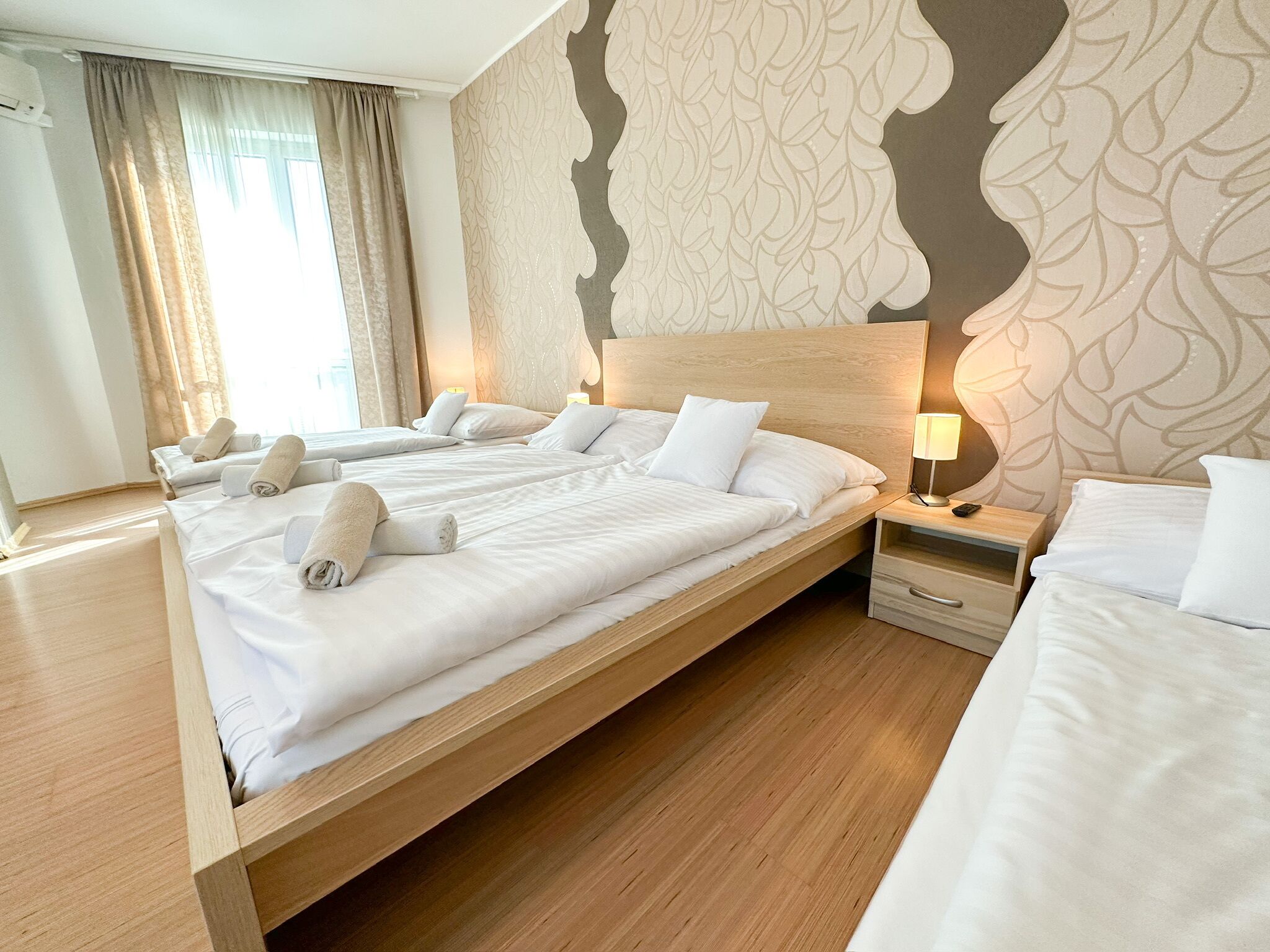 Ett hotellrum med en stor säng, två sängbord och en sänggavel med ett bladmotiv.