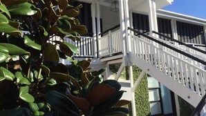 Un edificio de dos pisos con fachada blanca, un balcón y una escalera.