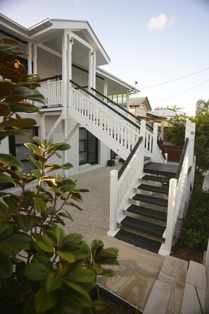 A white two-story house with a staircase leading to a balcony.