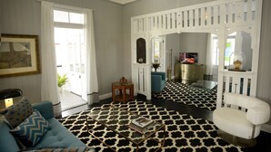 Una habitación con un sofá azul, una mesa de centro, una silla blanca y un suelo estampado.