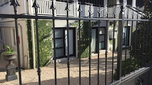 Una entrada portonada a un edificio con un balcón blanco y un camino de grava.