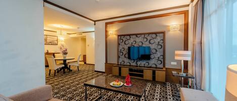 Une chambre d’hôtel avec un canapé, un coin repas, une télévision et une moquette à motifs.