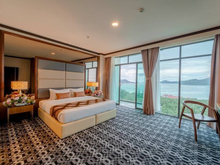 Ein Hotelzimmer mit einem großen Bett, einem Schreibtisch, einem Stuhl und Blick auf die Berge.