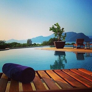 A poolside area with a wooden deck, a potted plant, and a lounge chair. - Adya Hotel Langkawi (Langkawi)