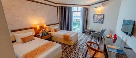 A hotel room with two beds, a desk, a chair, a TV, and a window with curtains.