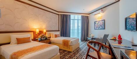 A hotel room with two beds, a desk, and a chair.