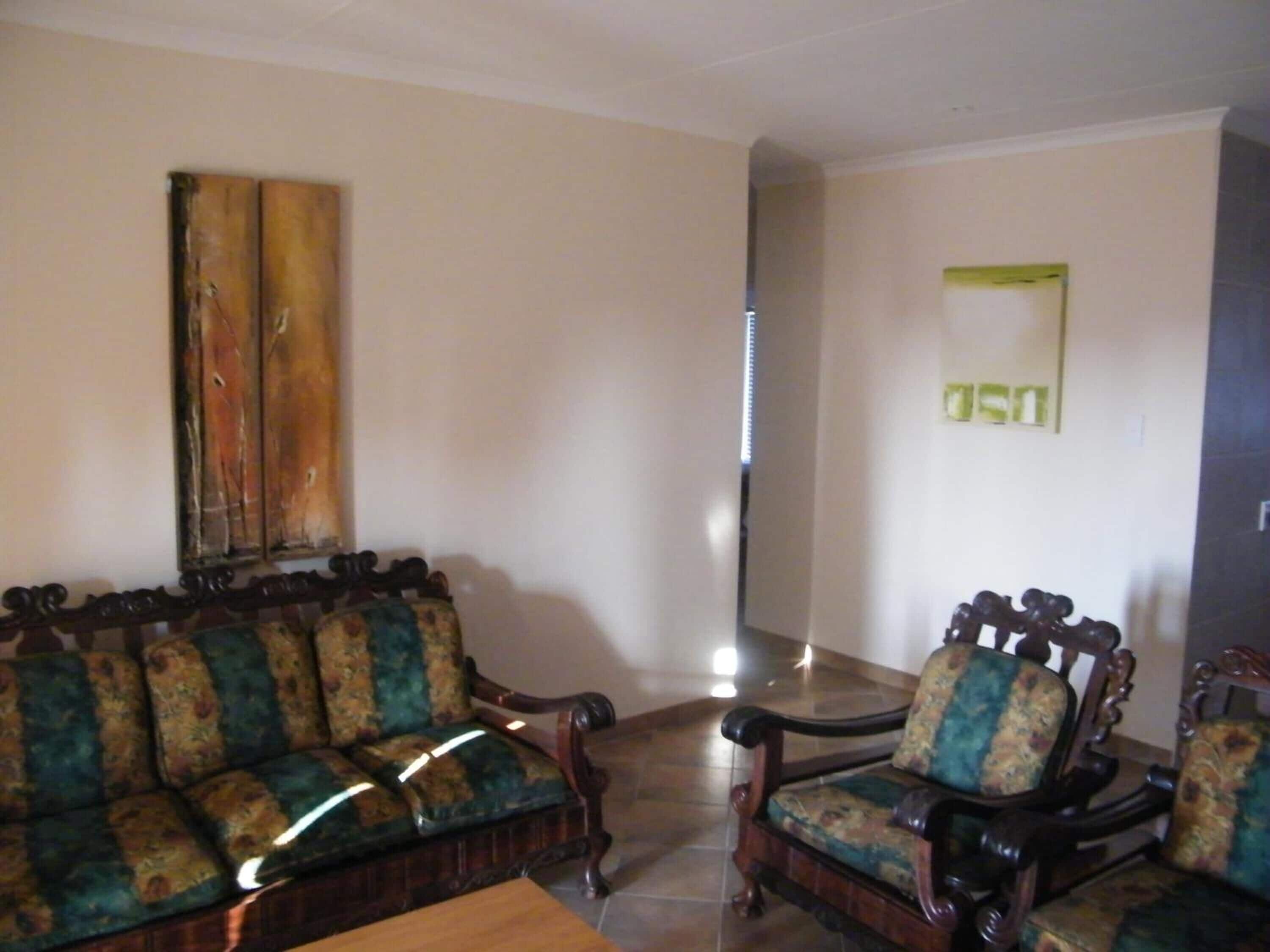 A living room with a sofa and two armchairs, a wooden coffee table, and a painting on the wall.