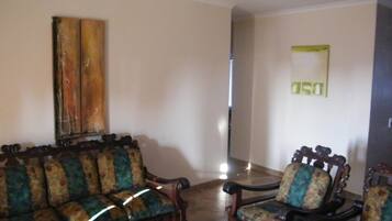 A living room with a sofa and two armchairs, a wooden coffee table, and a painting on the wall.