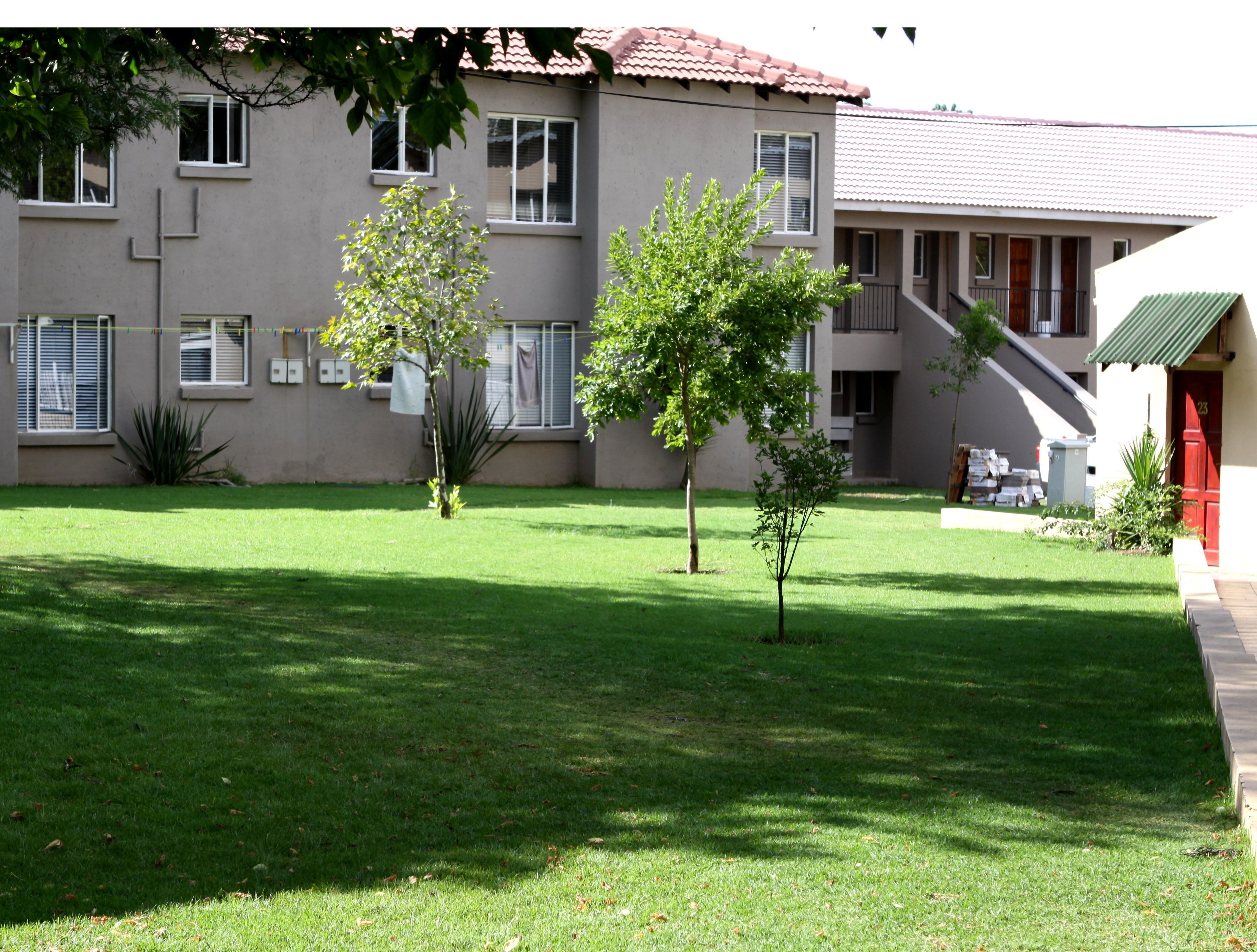 Un bâtiment doté d’un toit plat, de nombreuses fenêtres et d’une petite pelouse agrémentée de deux arbres.