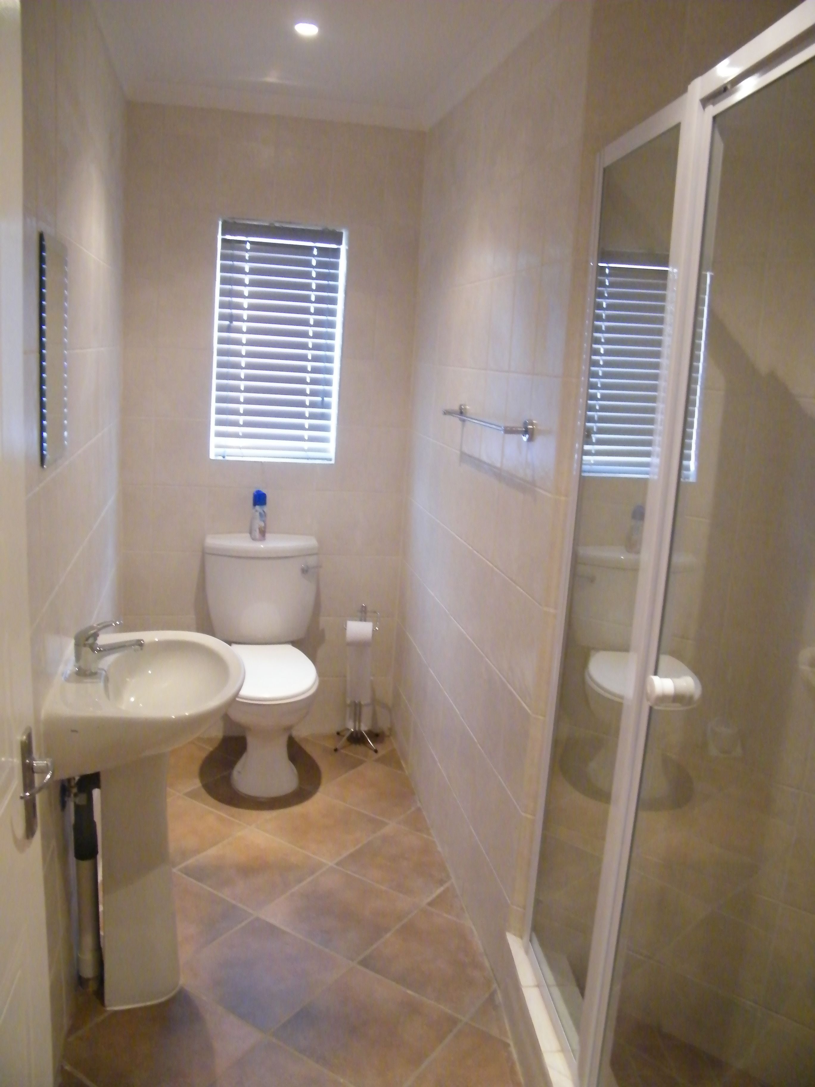 Un baño con inodoro, bidé y ducha con cerramiento de vidrio.