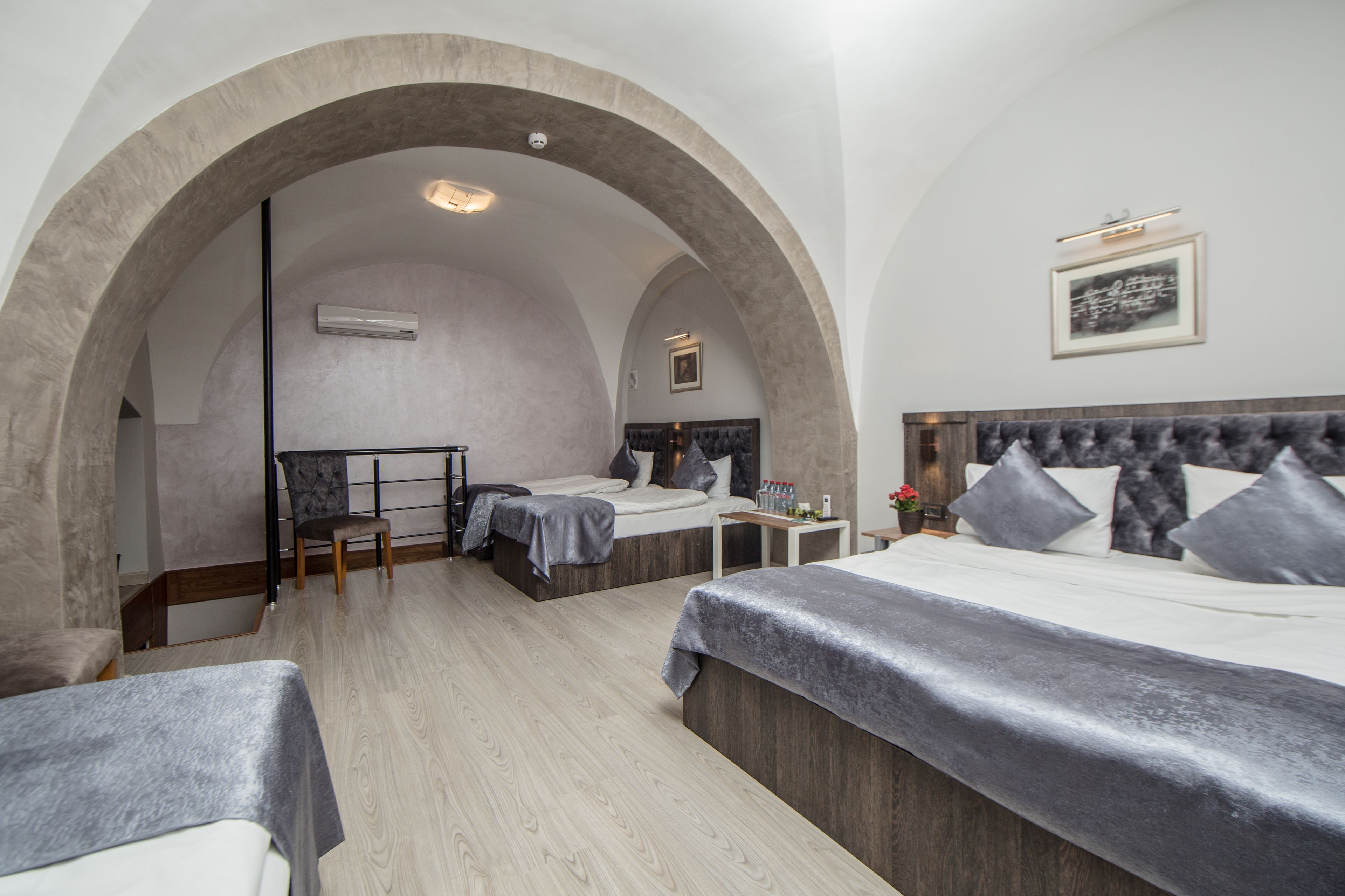 A hotel room with two beds, a seating area, and a large arched doorway.
