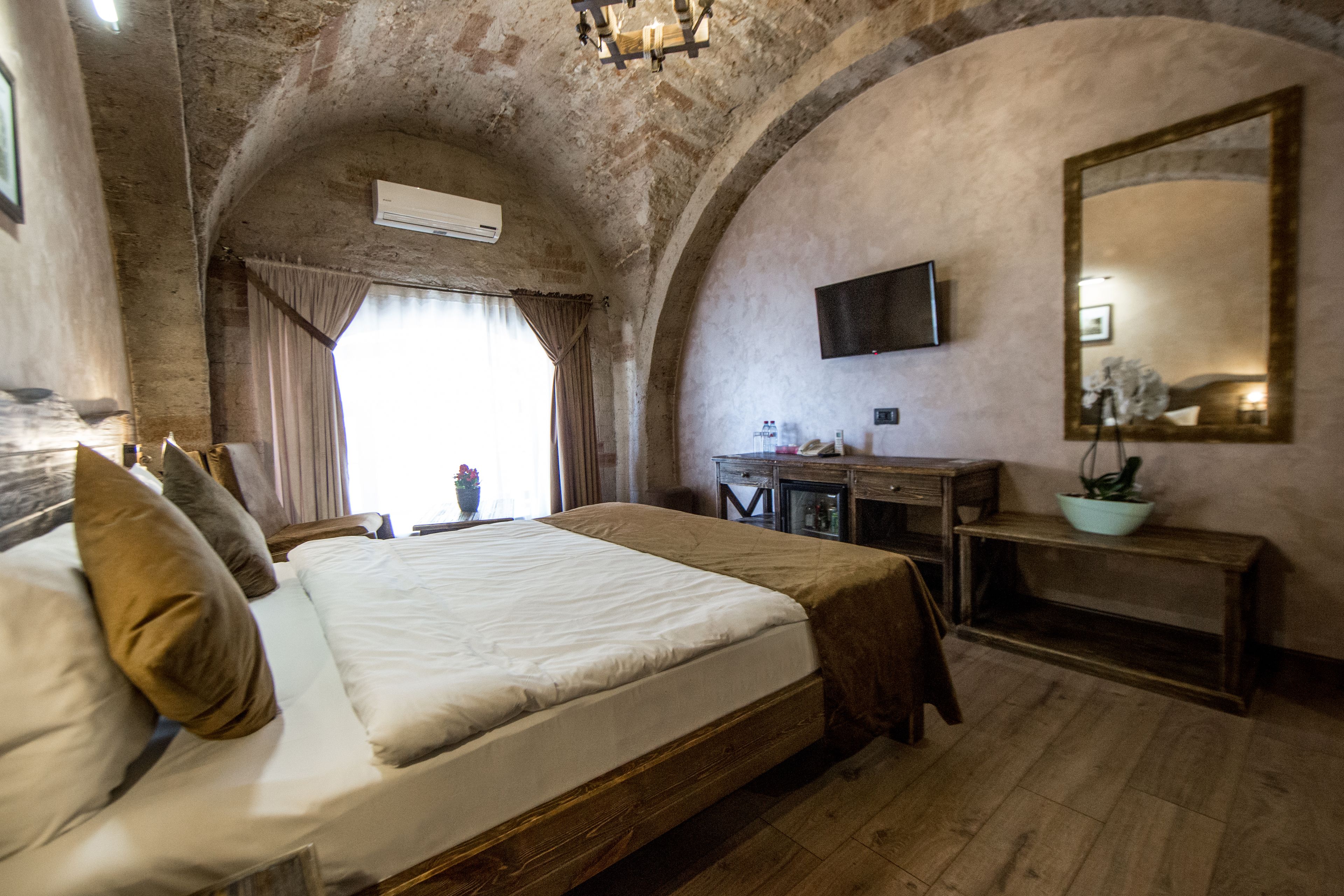 Una camera da letto con un letto grande, un comò in legno, uno specchio e un soffitto a volta.