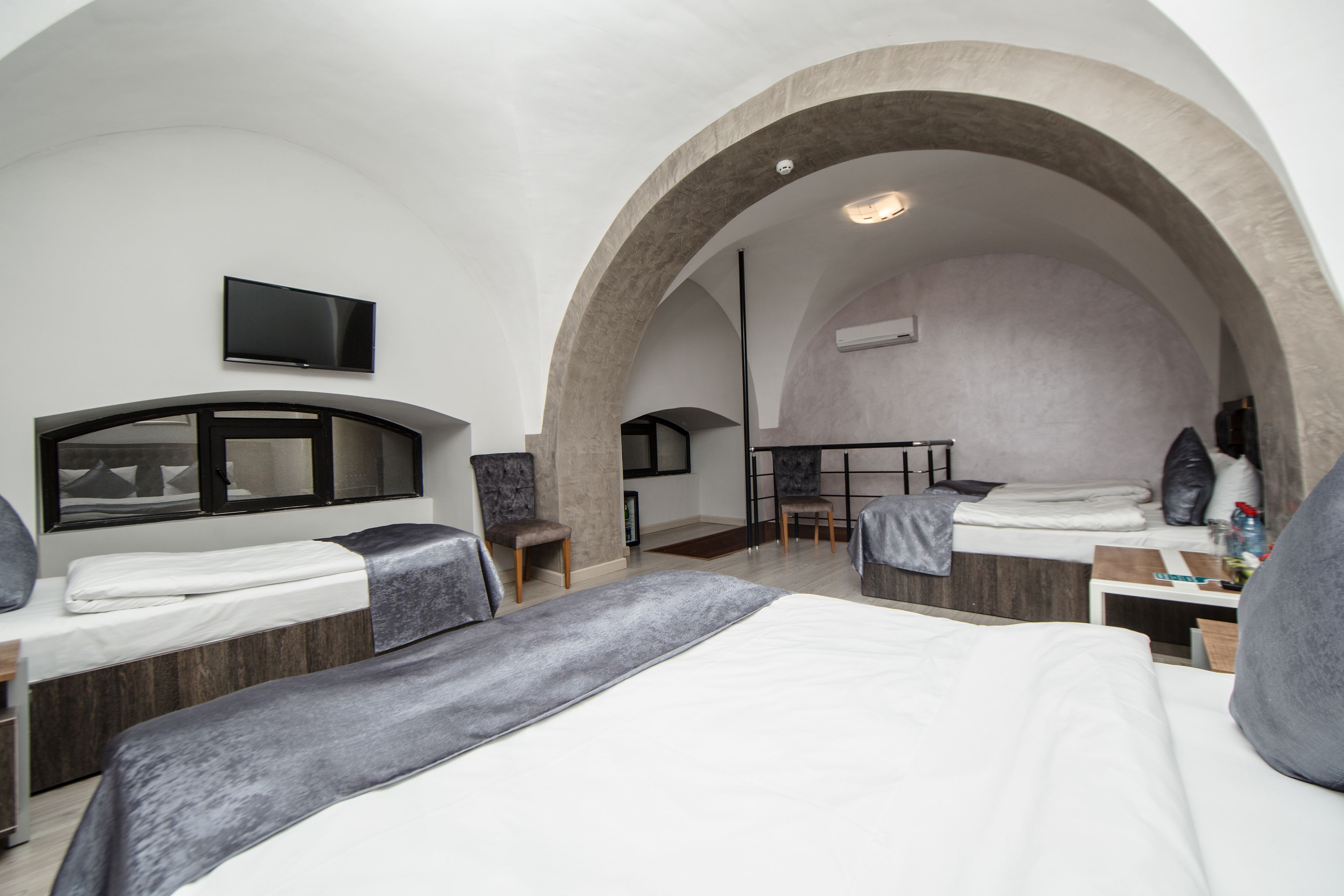 A modern hotel room with two beds, a TV, and a desk with chairs.