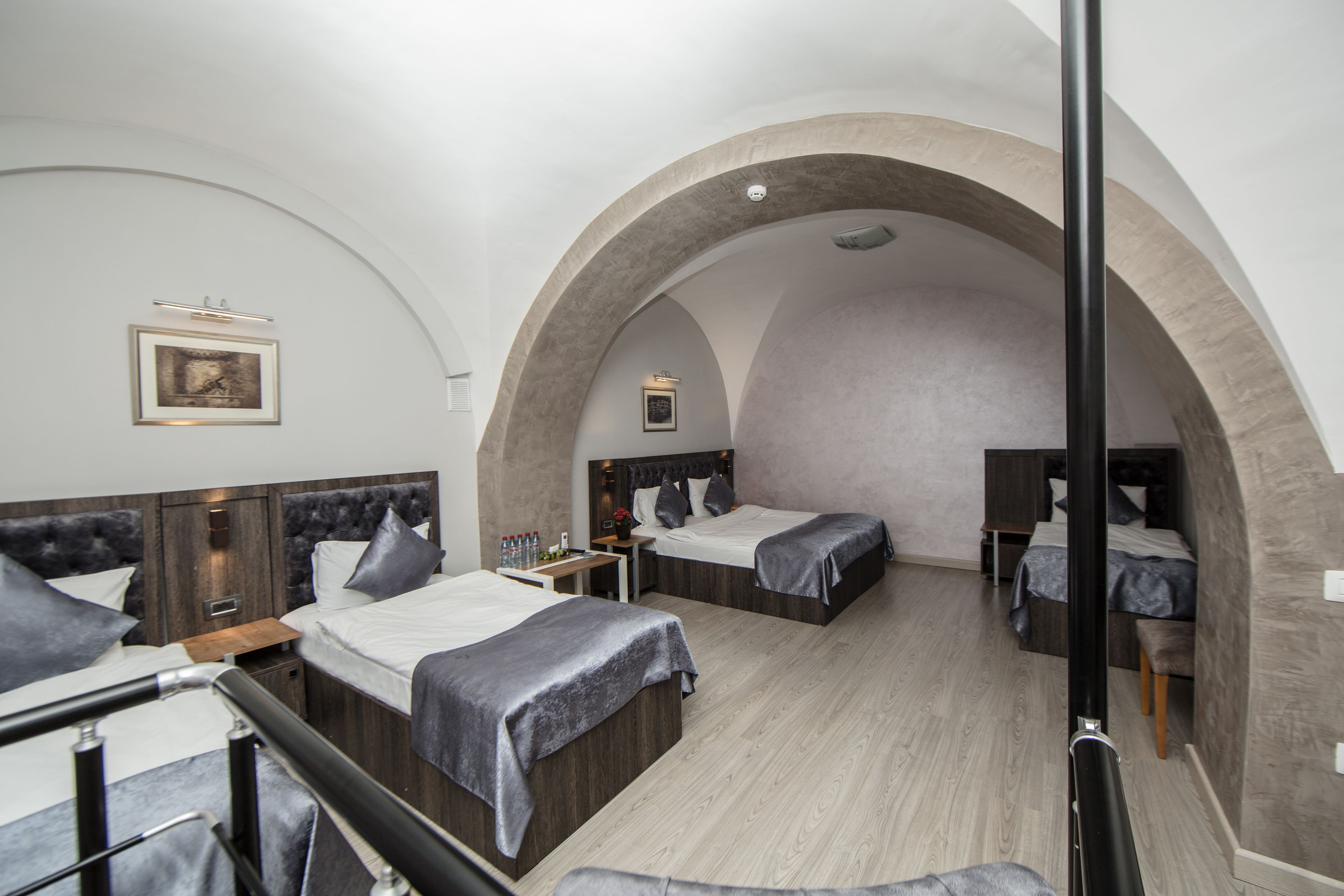 Ein Hotelzimmer mit zwei Betten, einem Holznachttisch, einem kleinen Tisch und einer Bank.