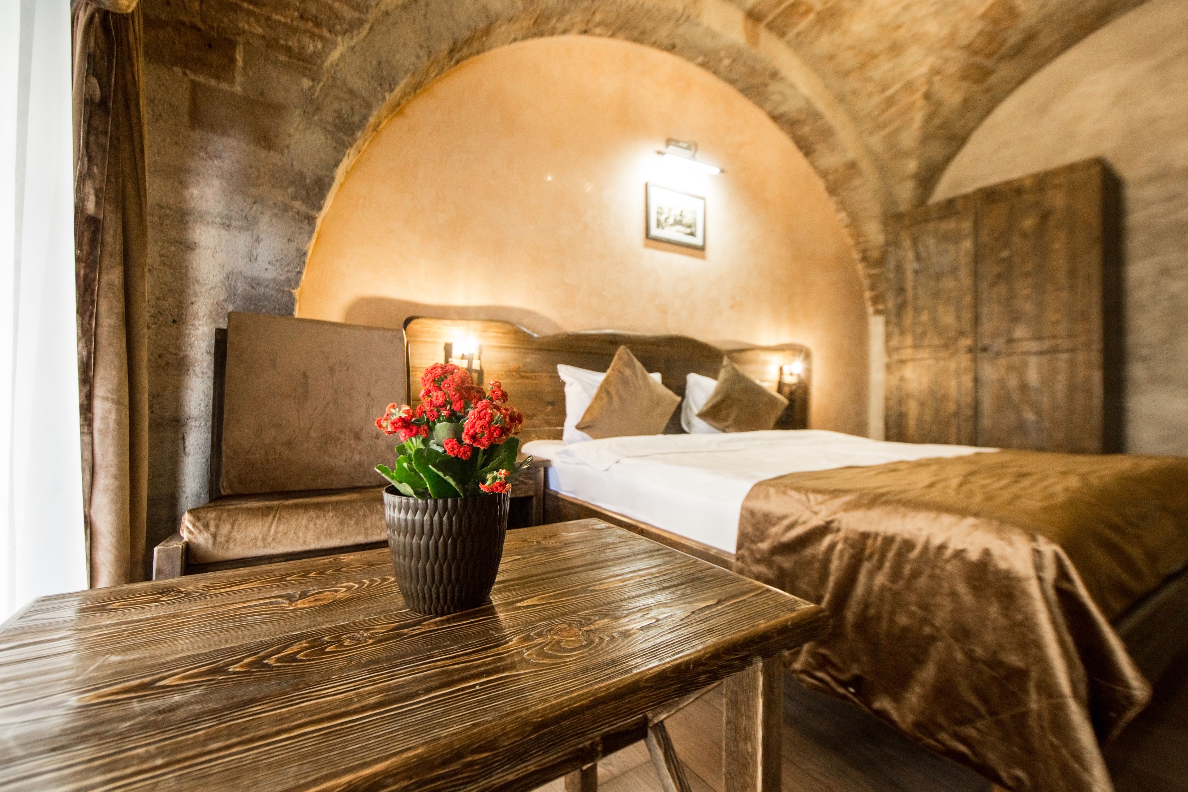 A cozy room with a wooden bench, a bed with pillows, and a vase of flowers on a table.