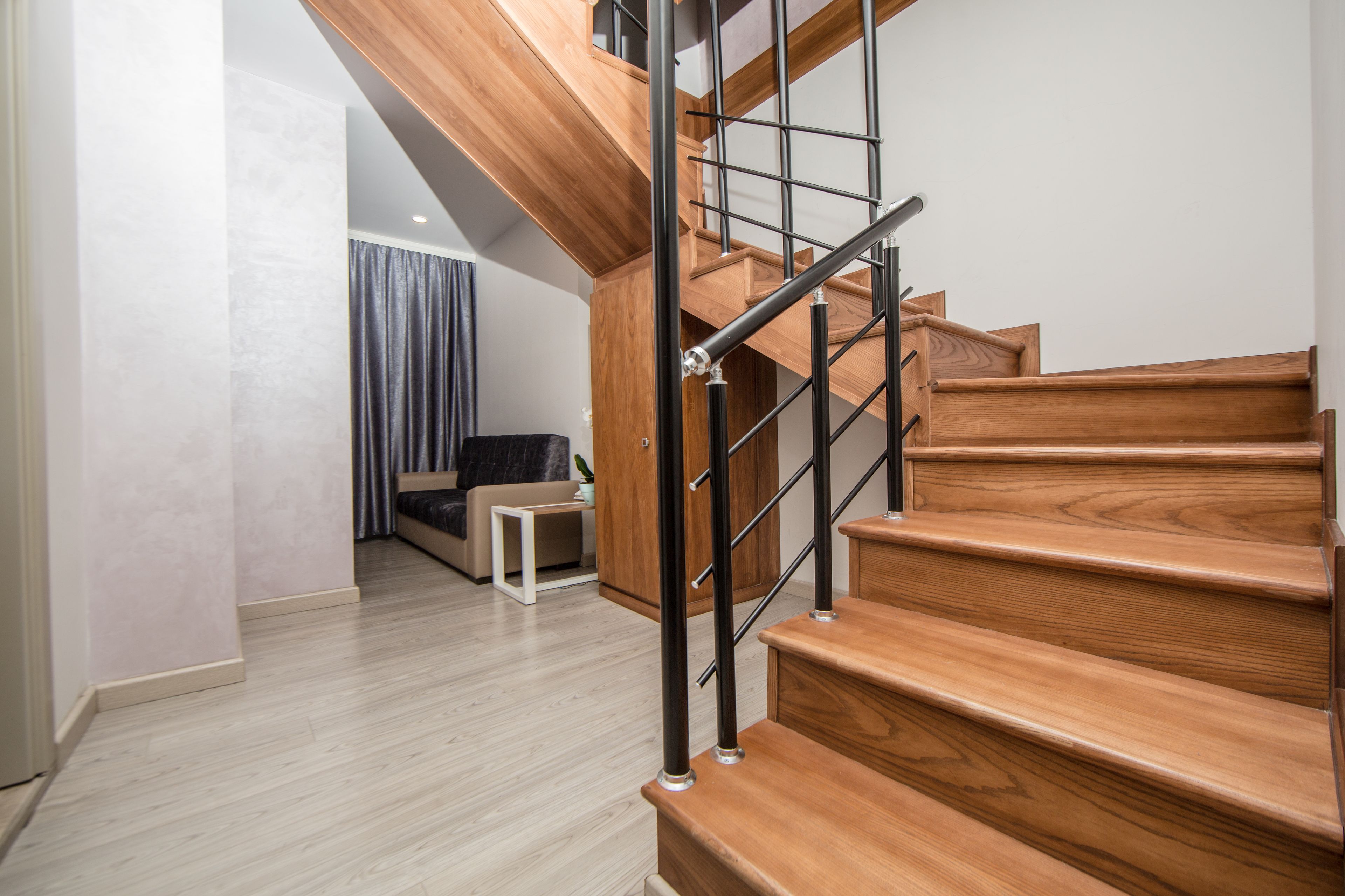 Una escalera moderna con peldaños de madera y barandillas de metal negro.