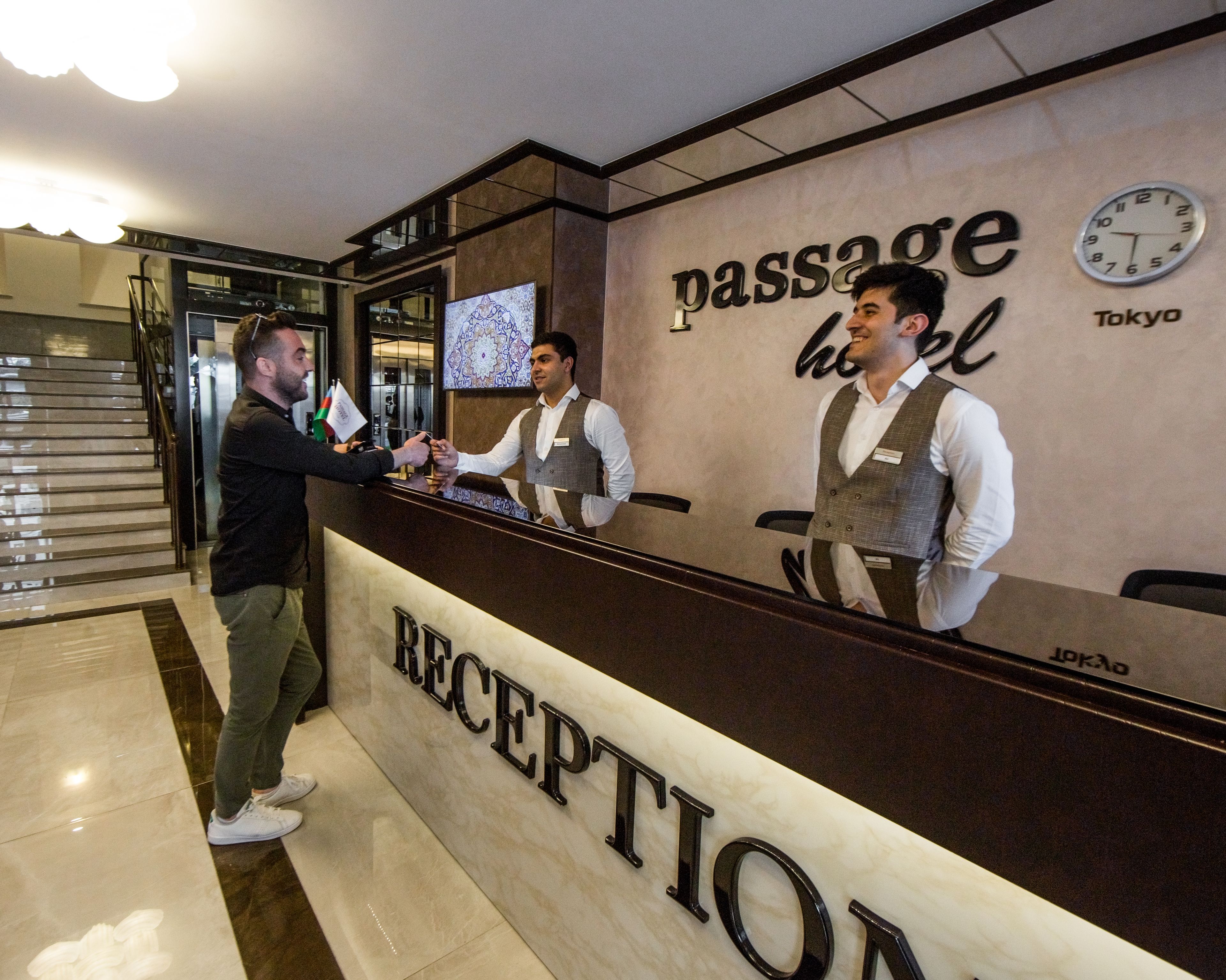 Un comptoir d’accueil avec une horloge et une pancarte indiquant « Passage Hotel Tokyo ».