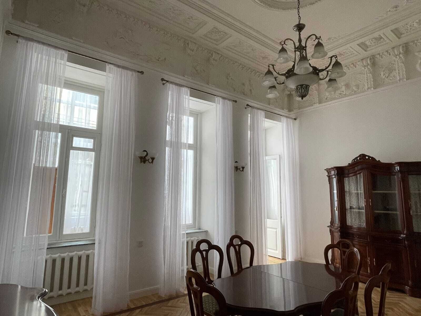 Ein Esszimmer mit einem großen Tisch, Stühlen, einer Chandelier und einem Schrank.