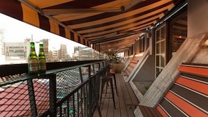 Un balcone con vista sulla città, pavimento in legno e due bottiglie di birra.