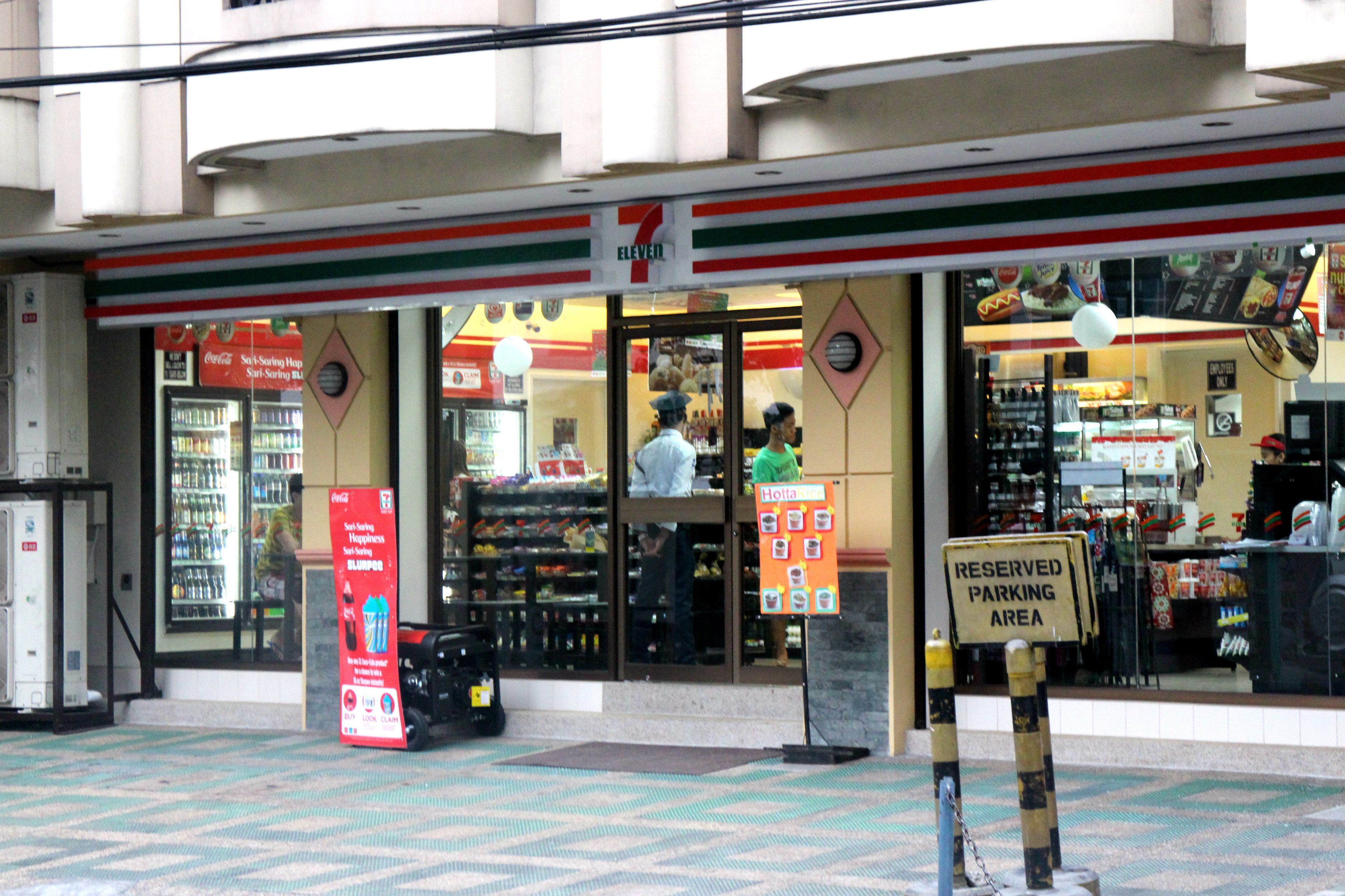 Una tienda de conveniencia 7-Eleven con un letrero de estacionamiento reservado, un refrigerador de Coca-Cola y una entrada visible.