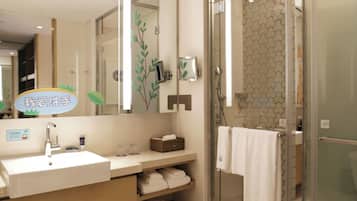 Un baño moderno con cabina de ducha de vidrio, lavamanos con espejo y un perchero para toallas.