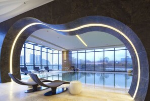 A modern indoor pool area with a large glass window, lounge chairs, and a unique architectural design. - Four Points By Sheraton Guilin, Lingui (Guilin)
