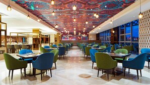 A spacious dining area with a patterned ceiling, multiple tables, and chairs. - Four Points By Sheraton Guilin, Lingui (Guilin)