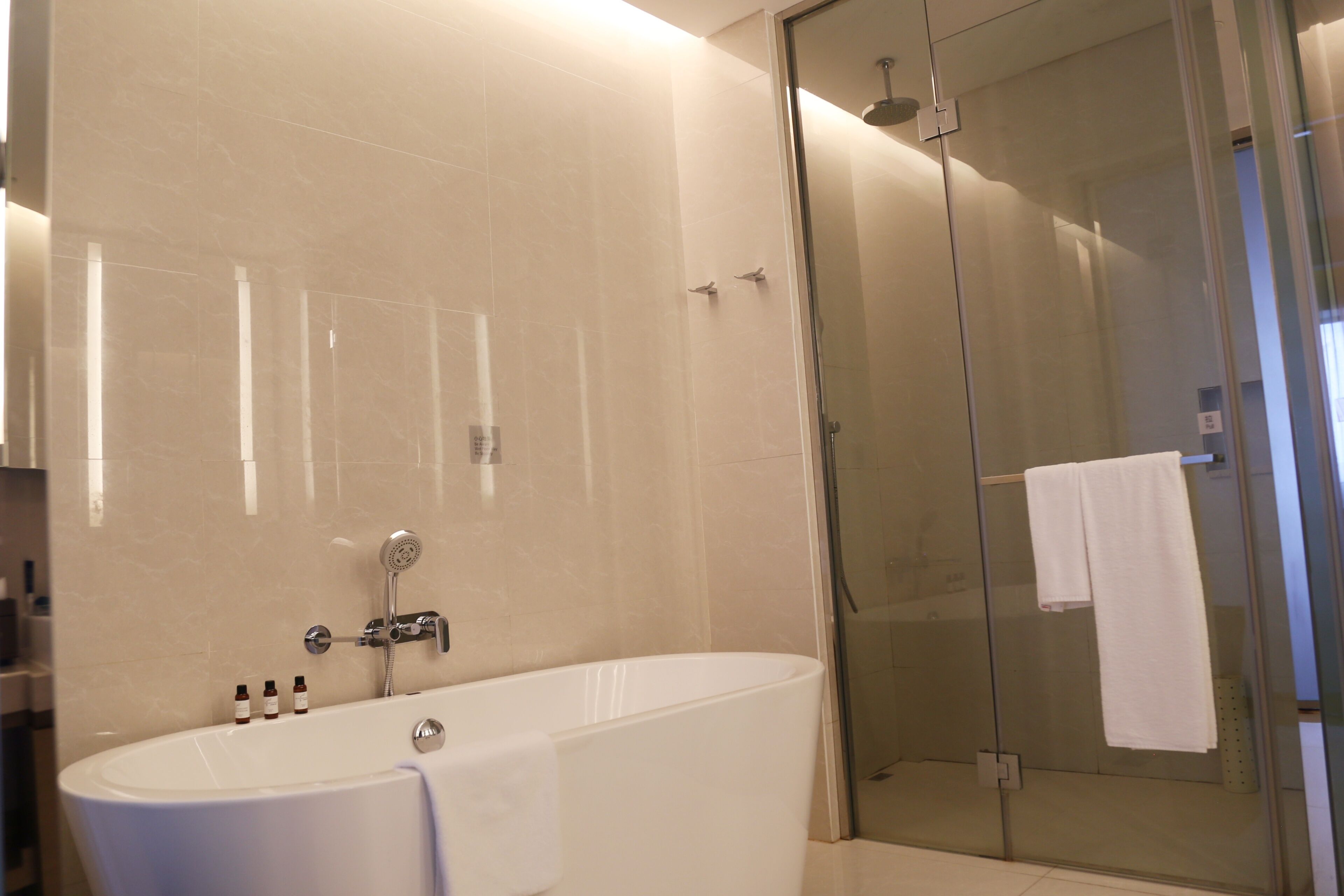 A modern bathroom with a freestanding bathtub, a glass-enclosed shower, and a glass door.