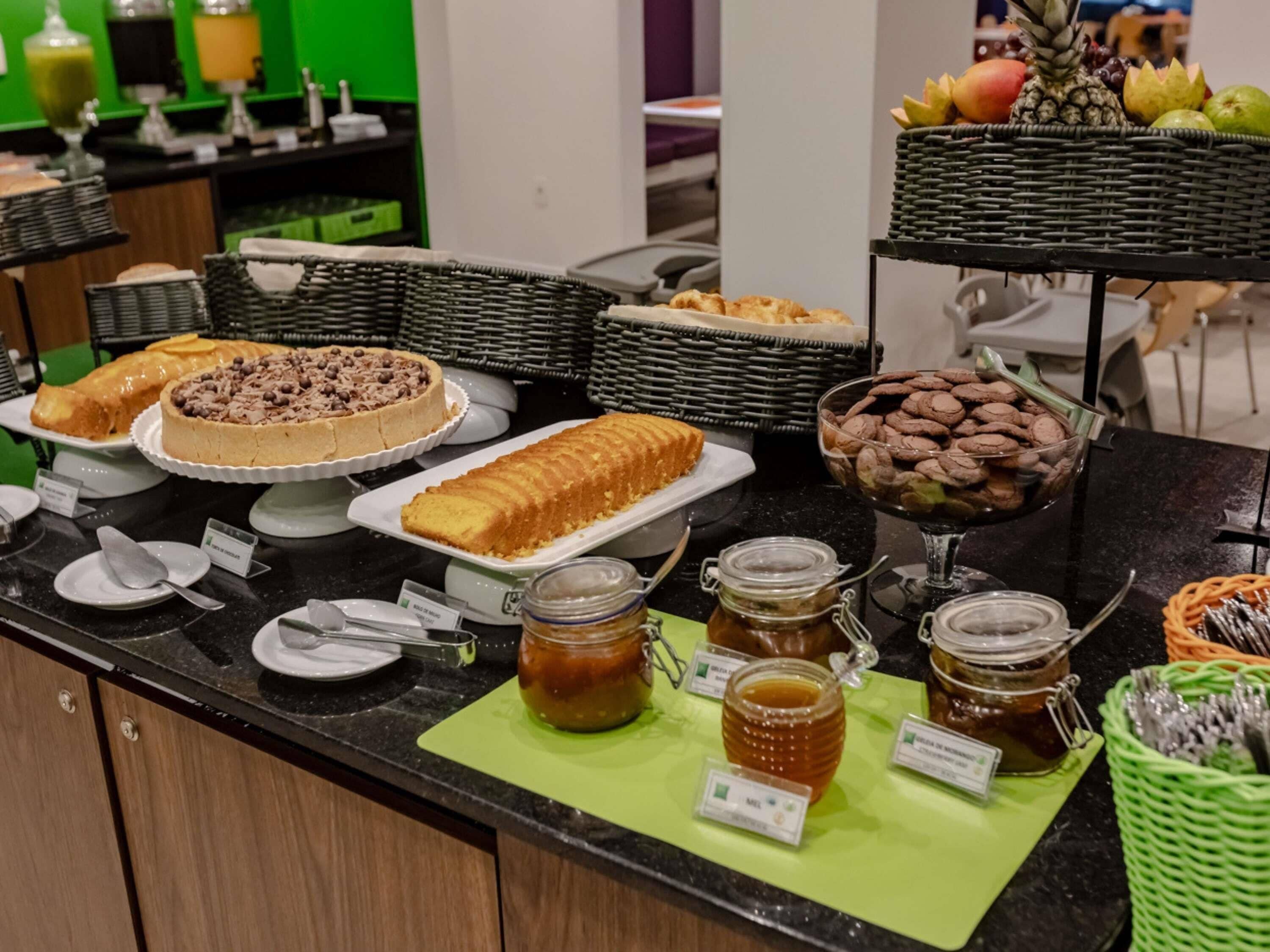 A buffet table with various food items including cakes, pastries, and jars of honey.