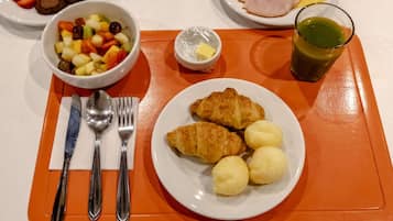 Uma mesa de café da manhã com croissants, ovos cozidos e uma cesta de frutas.