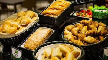 Un bufé con diversas opciones de panadería, incluyendo pan, croissants y pasteles.