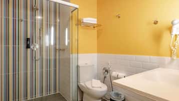 Un bany amb una cabina de dutxa de vidre, un vàter i una banyera.