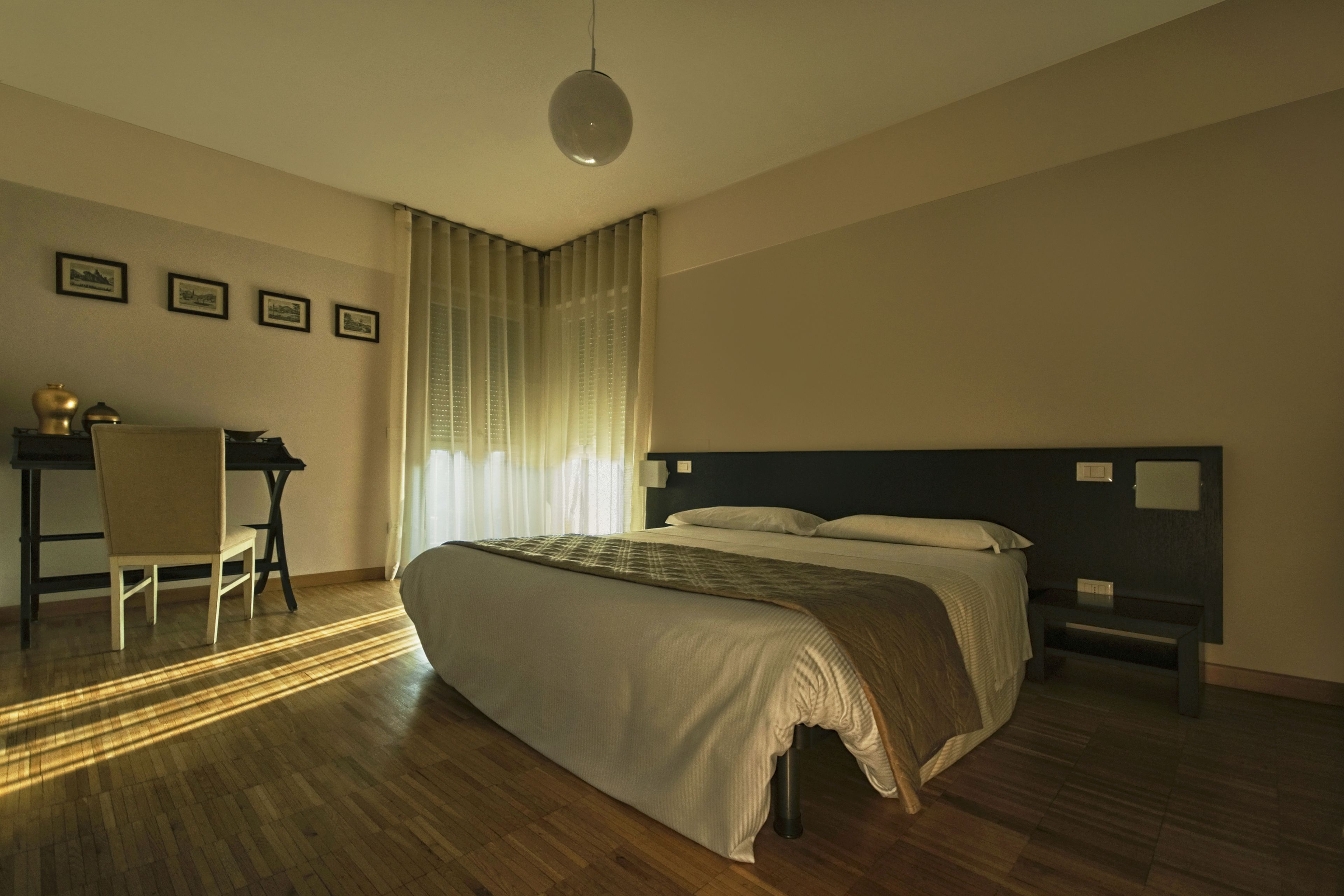 A bedroom with a large bed, a desk, and a chair.
