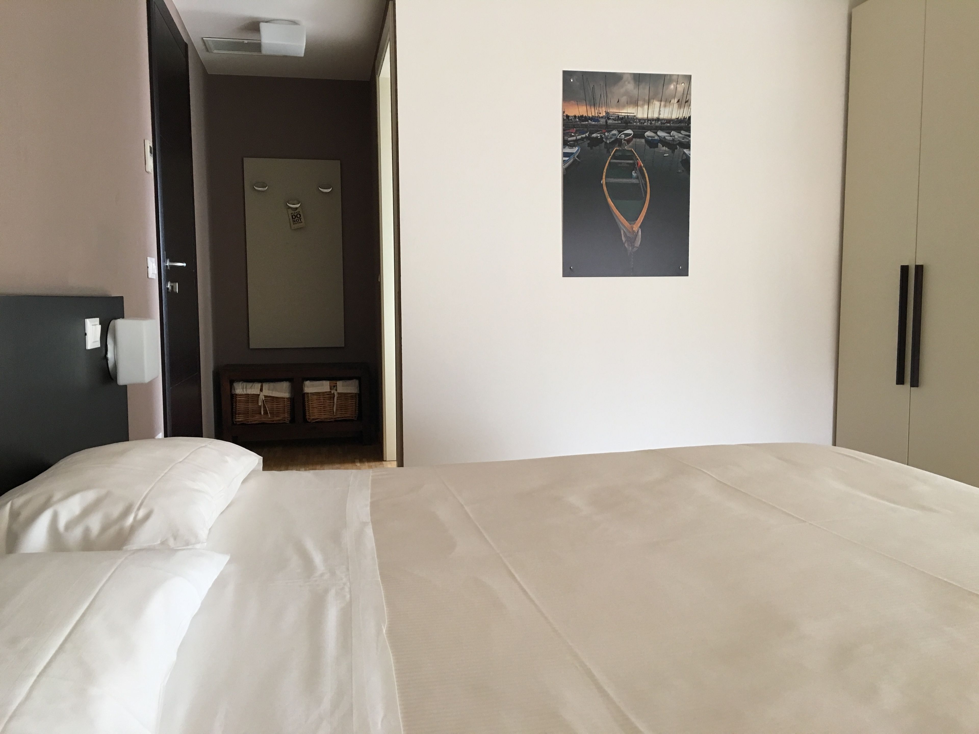 Habitación de hotel con cama, armario, puerta y un cuadro enmarcado en la pared.