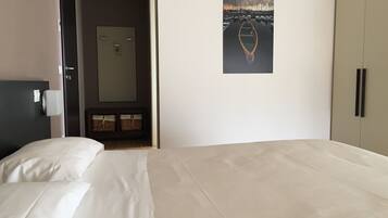 Habitación de hotel con cama, armario, puerta y un cuadro enmarcado en la pared.