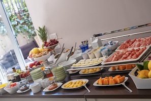 Ein reichhaltiges Buffet mit einer Auswahl an Speisen, darunter Früchte, Fleisch und Käse.